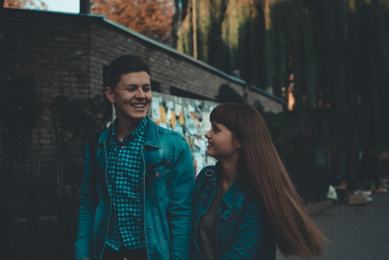 man and woman holding hands while walking down the street