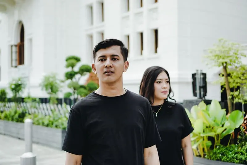 couple wearing black shirt with woman behind the man in the middle of the street