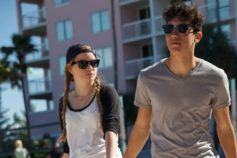Couple walking by the beachside wearing shades