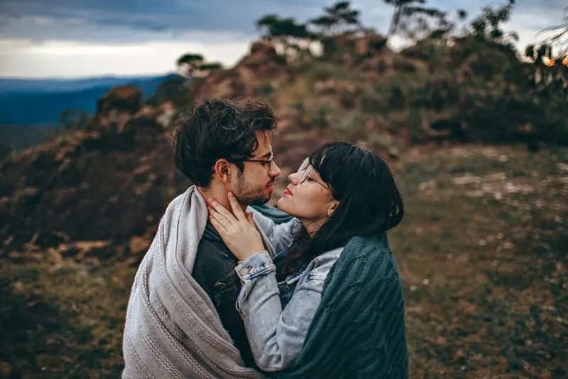 man and woman wrapped in blanket standing in field