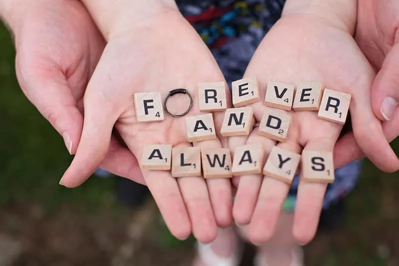couple's hands with scrabble letters forming forever and always with a ring on O