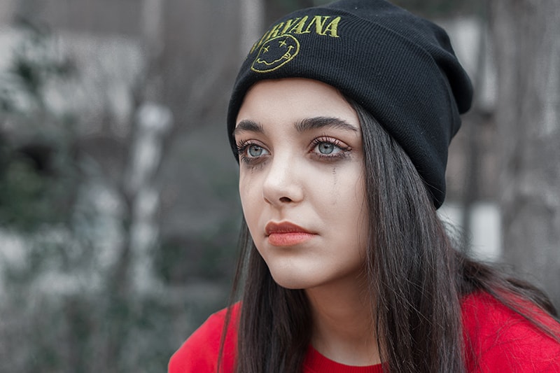 crying woman in black knit cap and red shirt