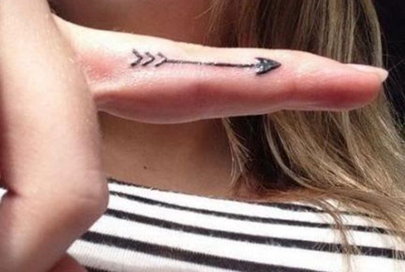 delicate arrow tattoo inside of the finger