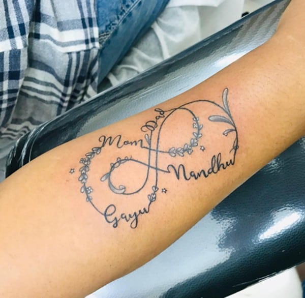 tatuaggio con doppio simbolo dell'infinito con nomi e fiori