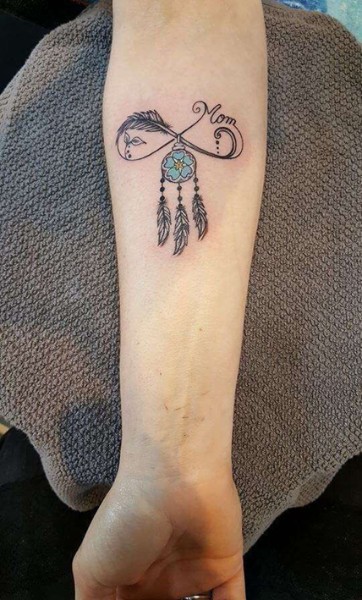 tatuaggio con disegno di acchiappasogni e piume sul braccio
