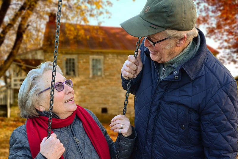 pareja de ancianos mirándose cerca del columpio