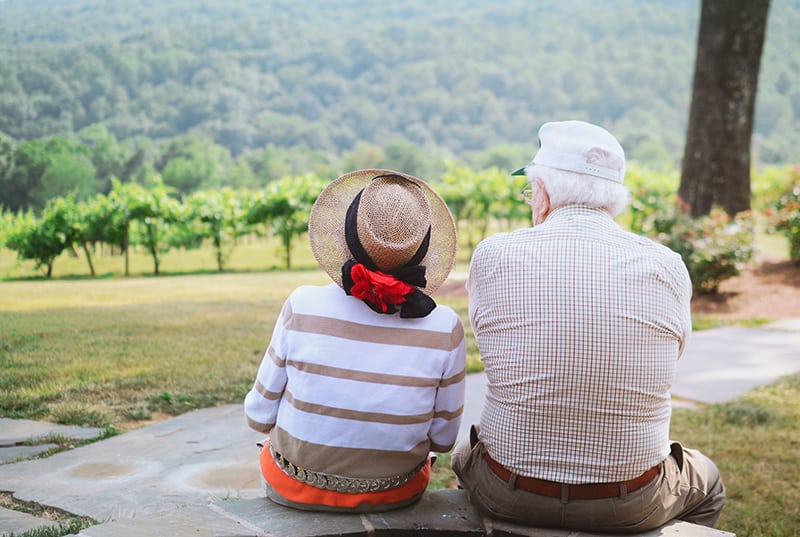 coppia di anziani seduta sul sentiero mentre guarda la natura