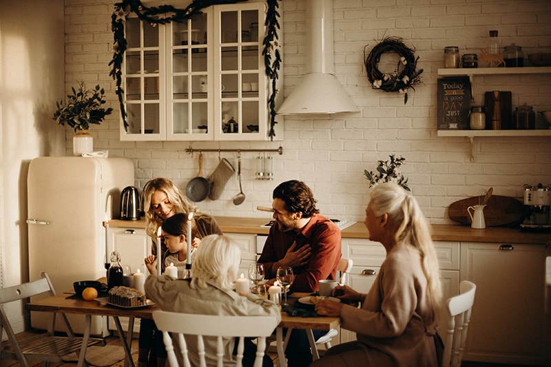 family sits by table in the kitchen