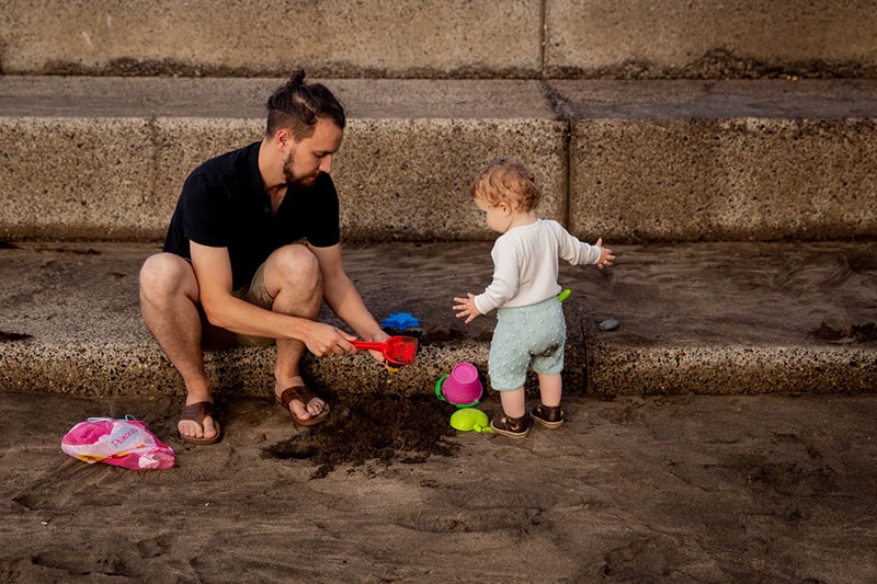 father and child playing with sand