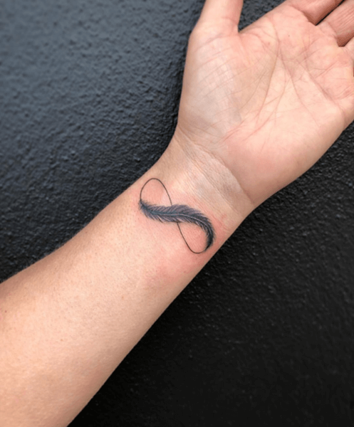 tatuaggio infinito con piume sul braccio