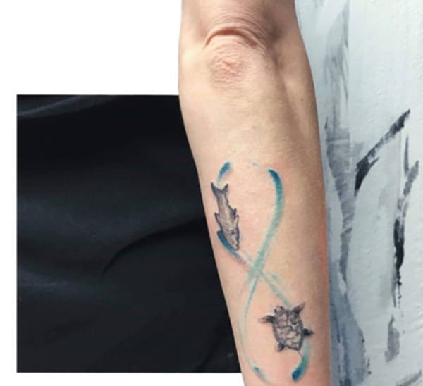 pesce e tartaruga all'interno del disegno del segno blu tatuaggio sul braccio