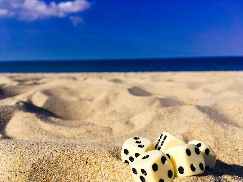 five dice on sand under blue sky