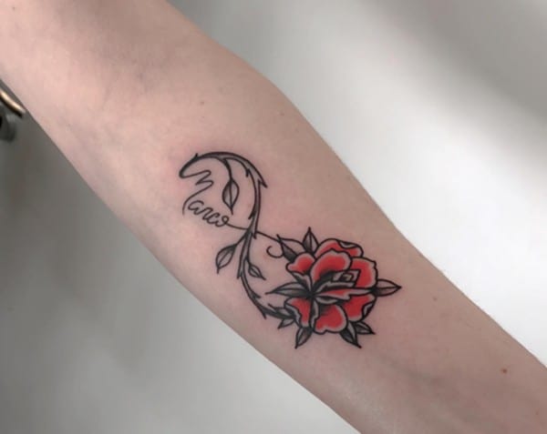 Tatuaggio con gambo di fiore e nome infinito sul braccio