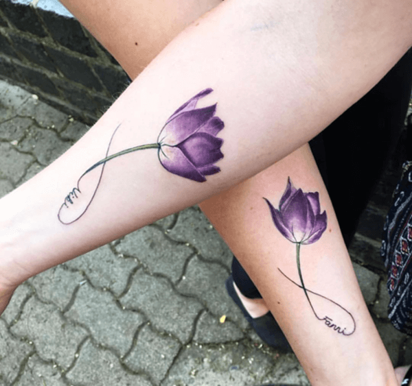 fiore viola con nome tatuaggio sul braccio