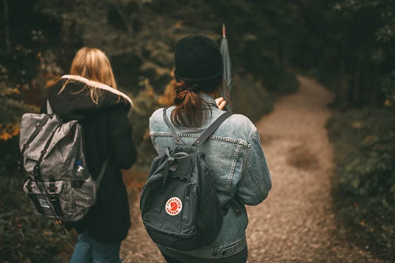 friends walking in the forest with backpack on their back