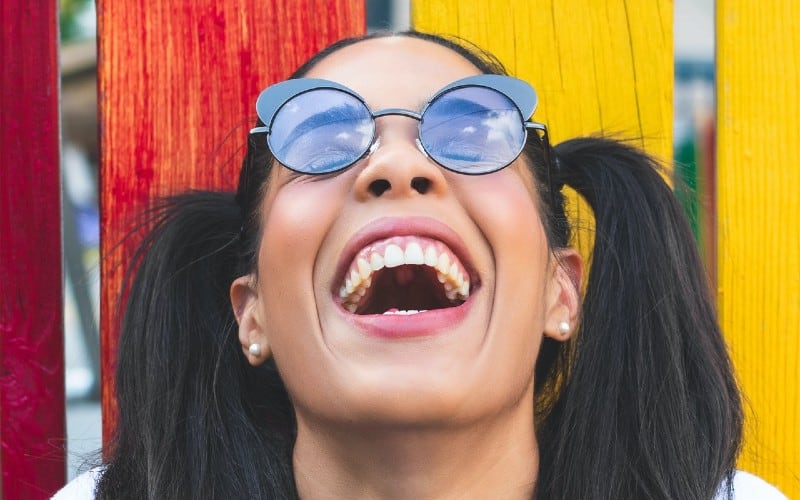 Funny woman laughing with her mouth opened wearing eyeglasses and two pony tails