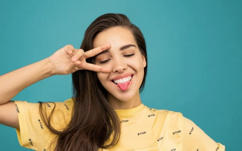Funny woman wearing yellow shirt with her tongue out of her mouth