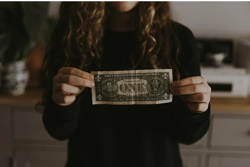 girl in black shirt standing and holding a banknote