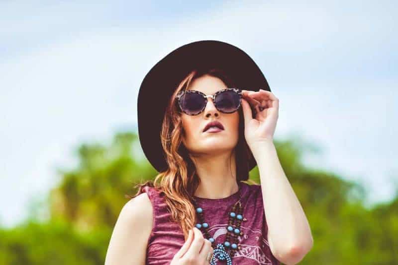 girl in pink tank top wearing black sun hat and black sunglasses