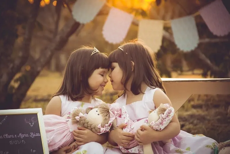 female twins playing with dolls outdoor