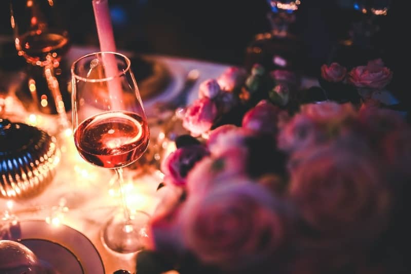 bicchiere di vino rosato sul tavolo vicino a fiori rosa