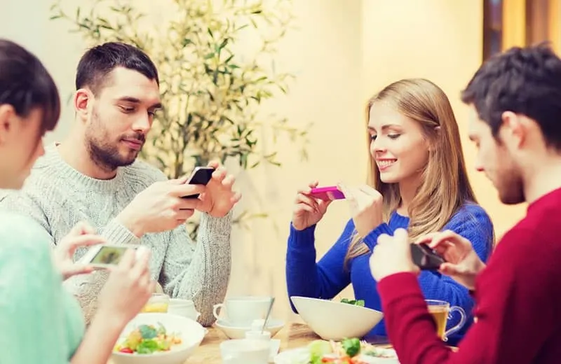 group of young people taking picture of the food in front of them in the table