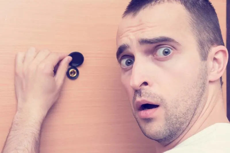 guy frightened looks on the camera after he looked at spy hole