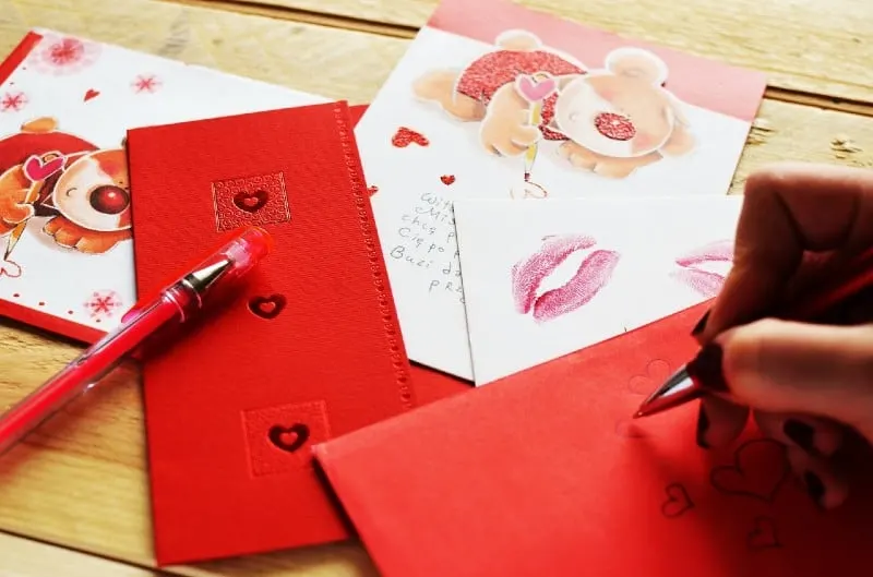 Woman hand writting love letter on red paper