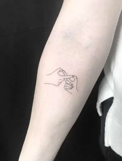 hands making infinity symbol tattoo on arm