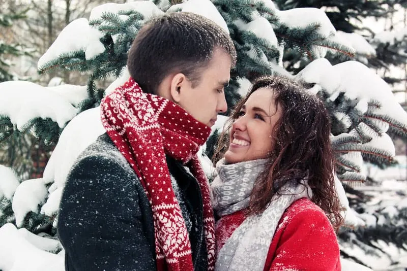 happy couple in snow smiling at each other