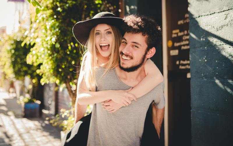 Happy man giving happy woman a piggyback ride outdoors during daytime