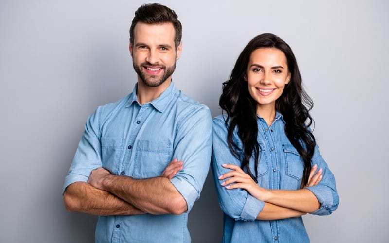 Homem feliz ao lado de uma mulher feliz, ambos com tops azuis