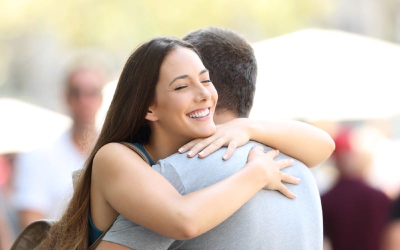 Mujer feliz abrazando a un hombre al aire libre duting día