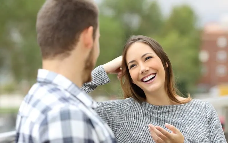 Happy woman talking to man sititing next to hom outdoors