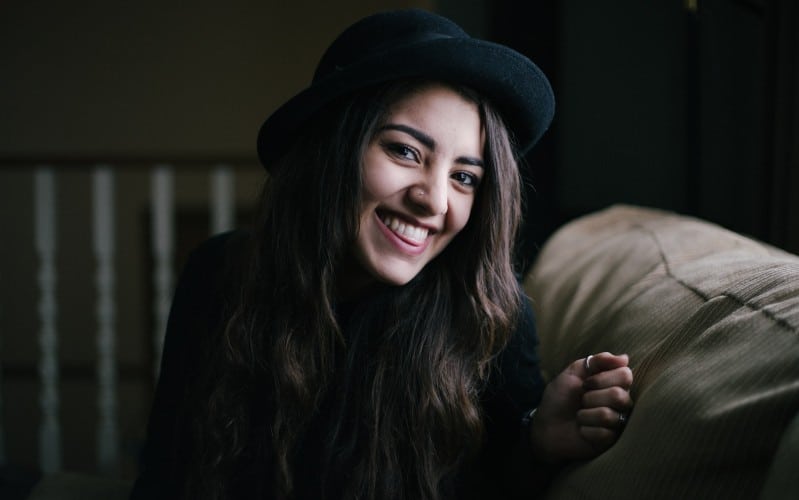 Happy woman wearing hat sitting and laughing