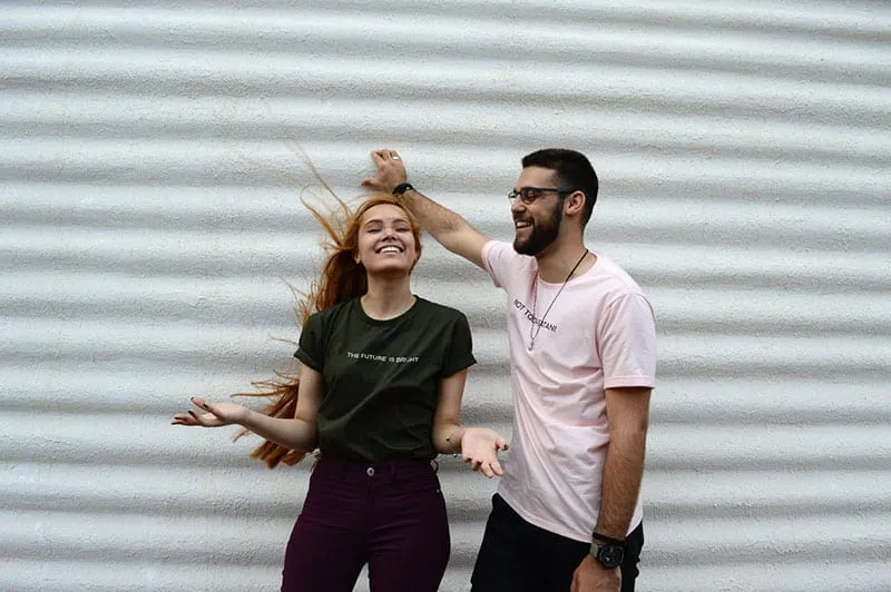 happy woman with hair blown beside a man in white shirt