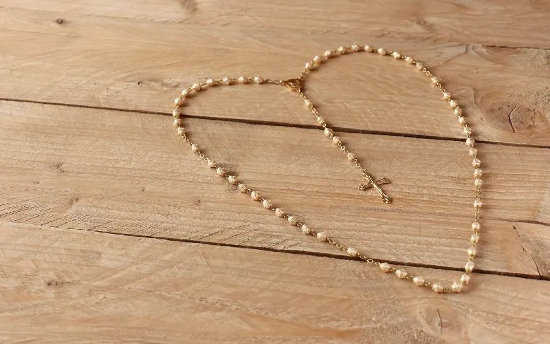 Heart shaped prayer rosary on wooden background