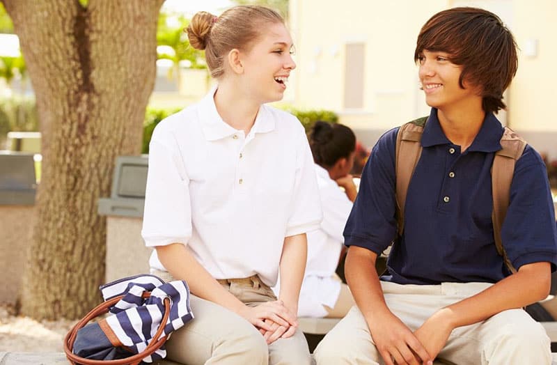 high school romance with school boy and girl sitting under a tree