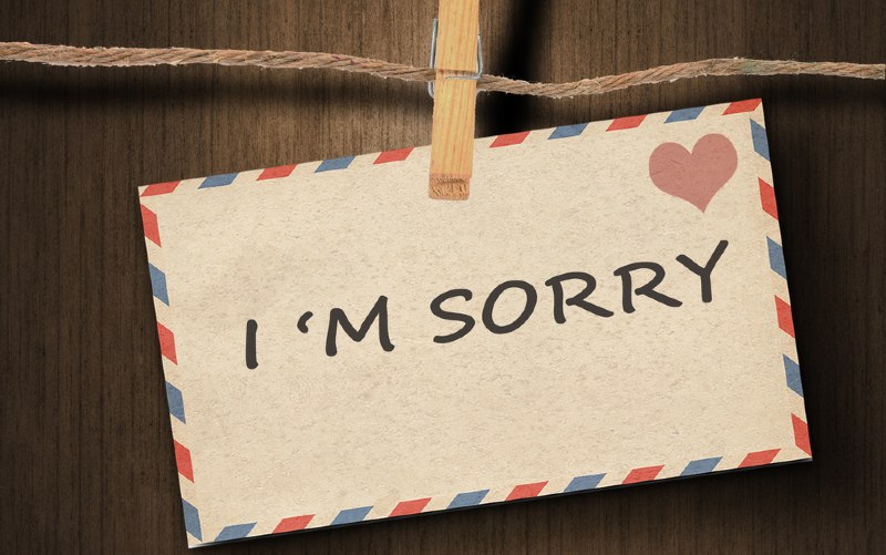 I am sorry message written on old envelope with brown wood background
