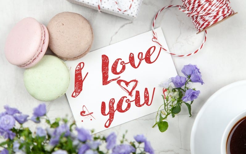 I love you message written on a piece of paper near flowers and-macarons