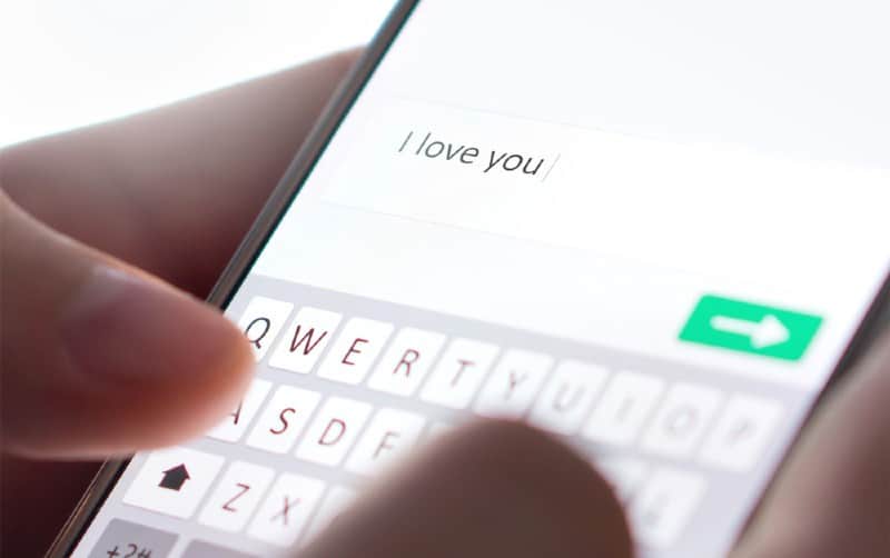 Mani che scrivono un messaggio d'amore su uno smartphone