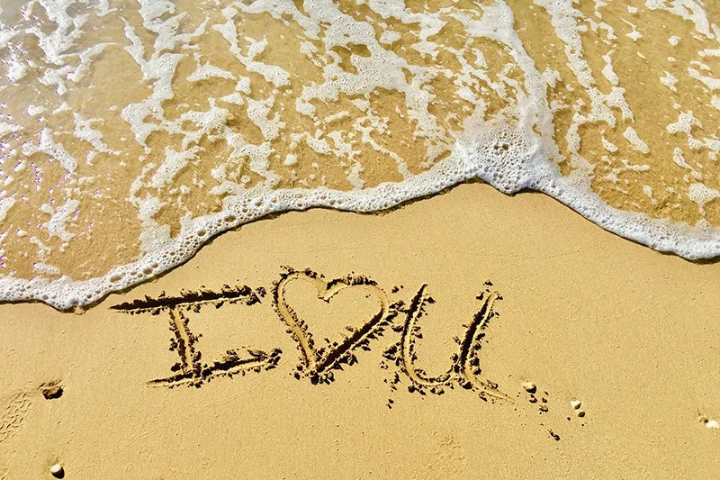 i love you text on the sand near the water