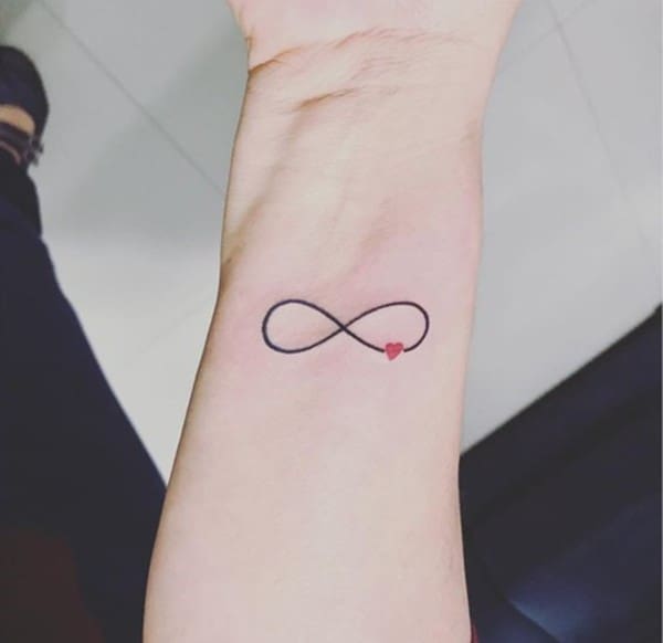 small infinity tattoo on wrist with a red heart