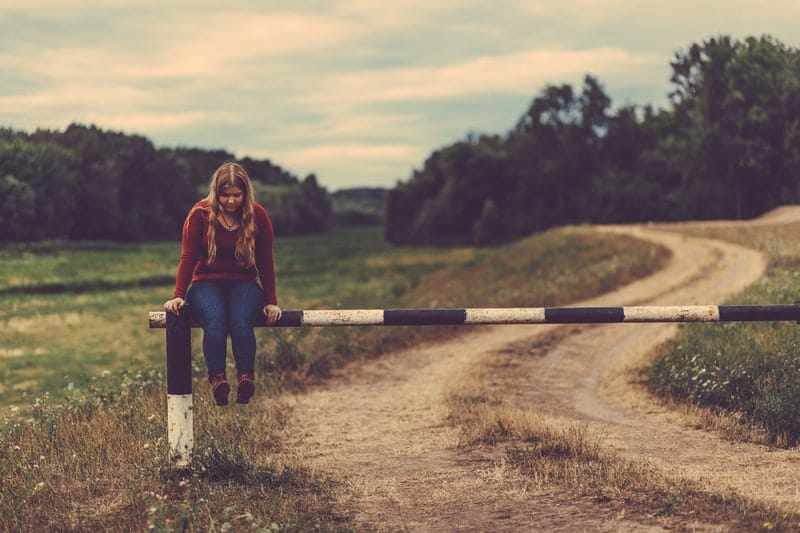 lonely woman on a steel boom gate near in the country side