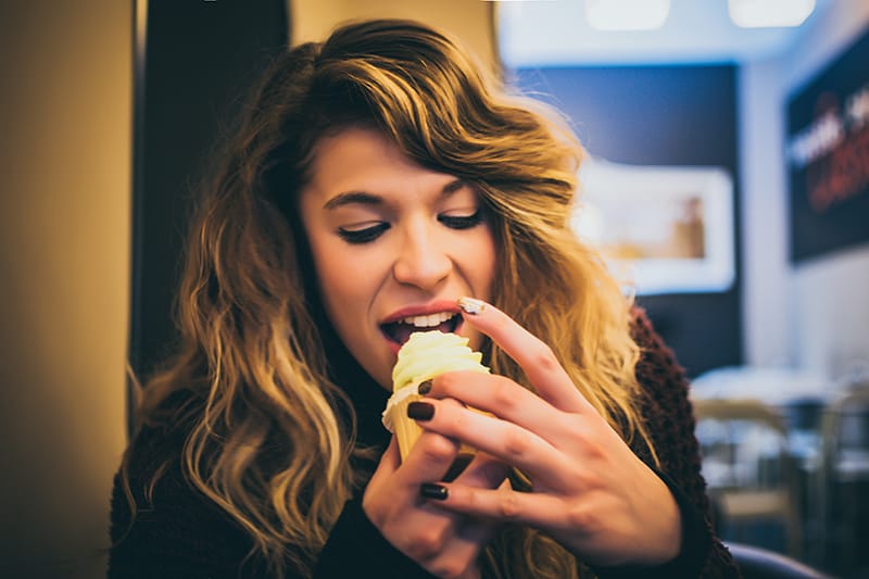 long blonde haired woman eating cupcake