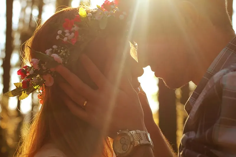 man about to kiss woman with flower wreath