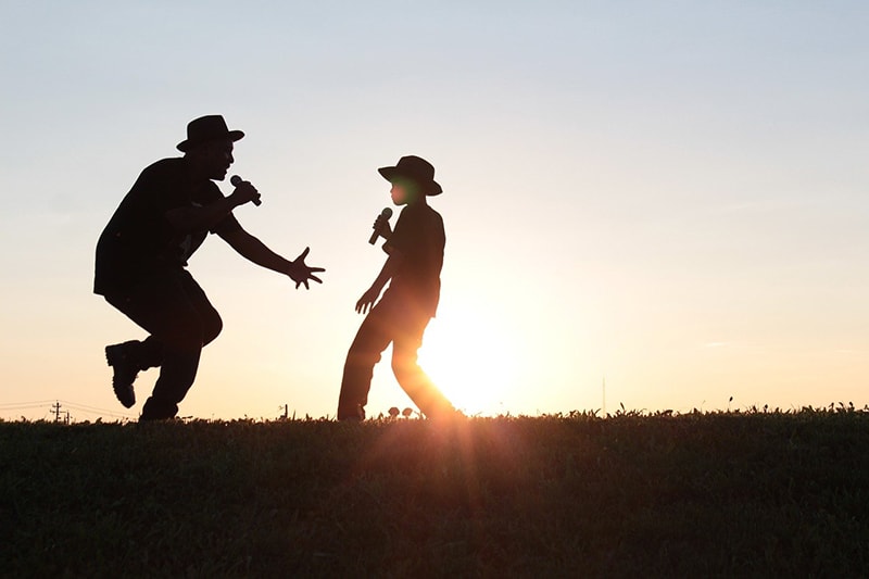 uomo e ragazzo che ballano e cantano durante il tramonto