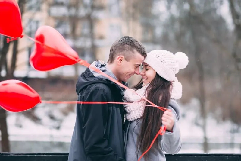 man and woman bringing 3 red heartshaped balloons