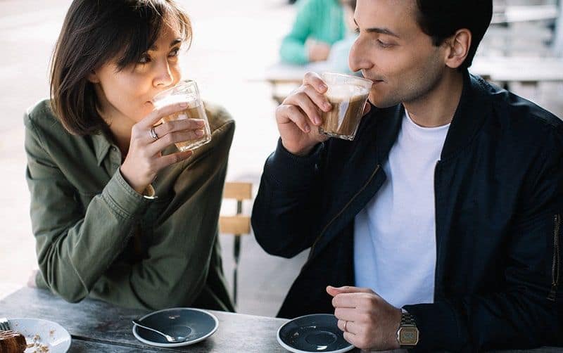 Man and woman drinking coffee from plastic cups