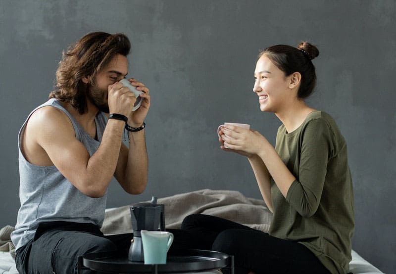 man and woman having breakfast near a gray wall